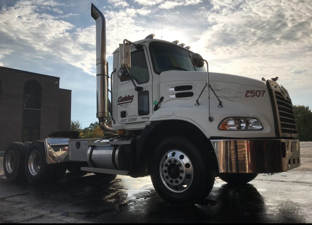 White Mack day cab unit 2507, washed and polished, in front of the brick office with the sun behind clouds