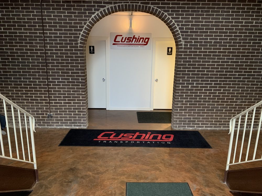 The office lobby: a brick arch, the Cushing Transportation Inc. sign, a Cushing floor mat and two stair rails