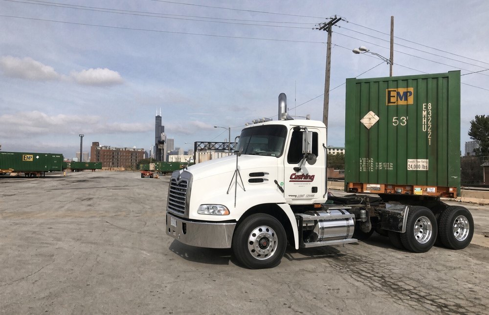 Cushing tractor 2507 under a 53 foot EMP container on a chassis at a Chicago rail ramp, the Willis Tower on the skyline behind