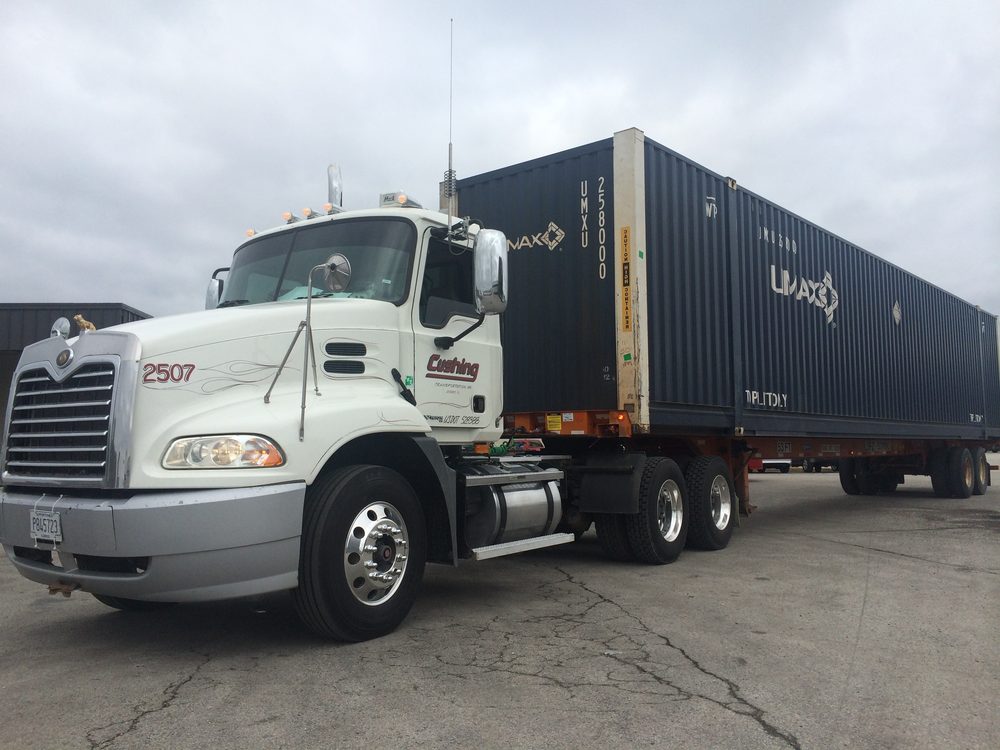 Cushing day cab 2507, Cushing Transportation lettering and USDOT 528388 on the door, with a dark UMAX container on its chassis in a paved lot