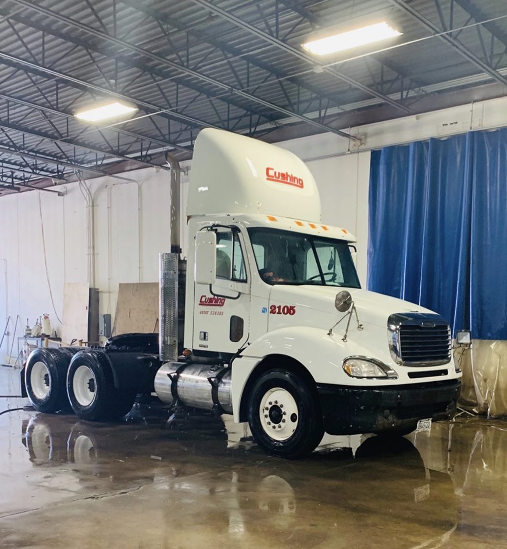 White Freightliner day cab unit 2105, Cushing on the roof fairing and the door, in the wash bay
