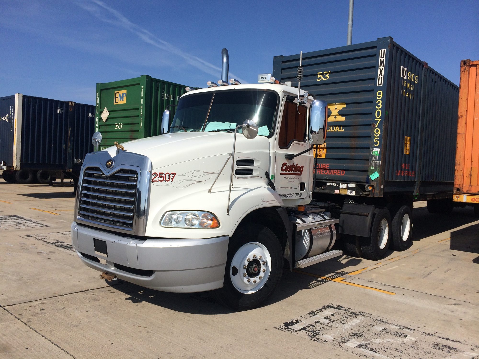 A Cushing tractor hooked to a container in a Chicago yard, stacked EMP and UMXU intermodal boxes behind it